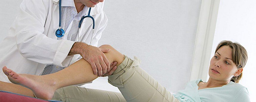 Врач обследует колено пациента Врач обследует колено