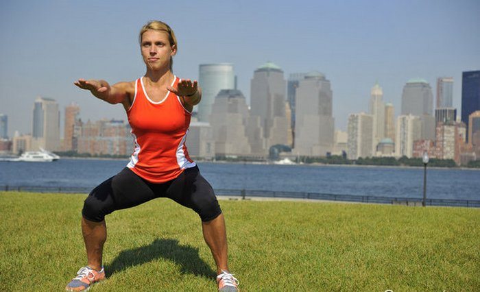 Девушка выполняет приседания Боли в колене при приседаниях