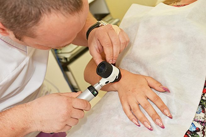 Врач обследует запястье пациента Диагностика гигромы запястья